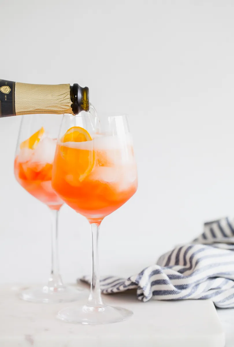 Ein fertiger Rhabarber Aperol Spritz mit Eis, Orangenzeste und Rhabarberdeko.