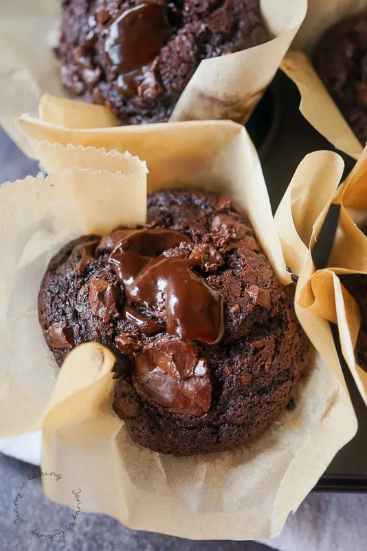 Ein fertiger Schoko Muffin wird auseinandergebrochen, um die reichhaltige, geschmolzene Schokoladenfüllung im Inneren zu zeigen, was die Köstlichkeit des Desserts hervorhebt