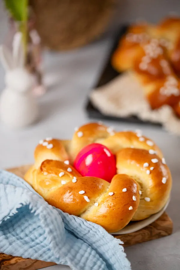 Ein fertiges Osternest mit einem bunten Osterei auf einem hübschen Teller, dekoriert mit einer Serviette