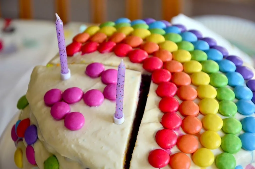 Ein festlich gedeckter Geburtstagstisch mit zwei Regenbogen-Torten als Mittelpunkt