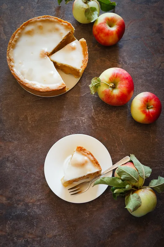 Ein frisch gebackener gedeckter Apfelkuchen in einer Springform, bestreut mit Puderzuckerglasur, bereit zum Servieren.