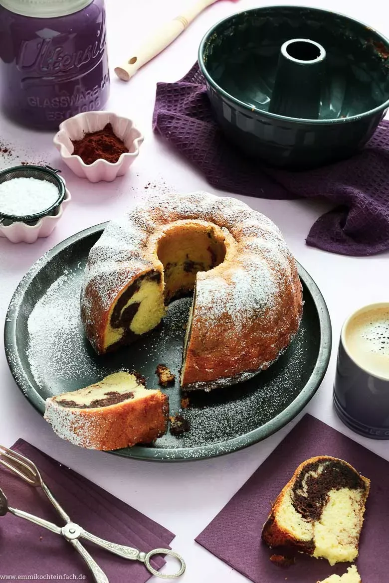 Ein frischer Marmorkuchen in einer Gugelhupf-Form, angeschnitten, um das charakteristische Marmormuster aus hellem und dunklem Teig zu zeigen.