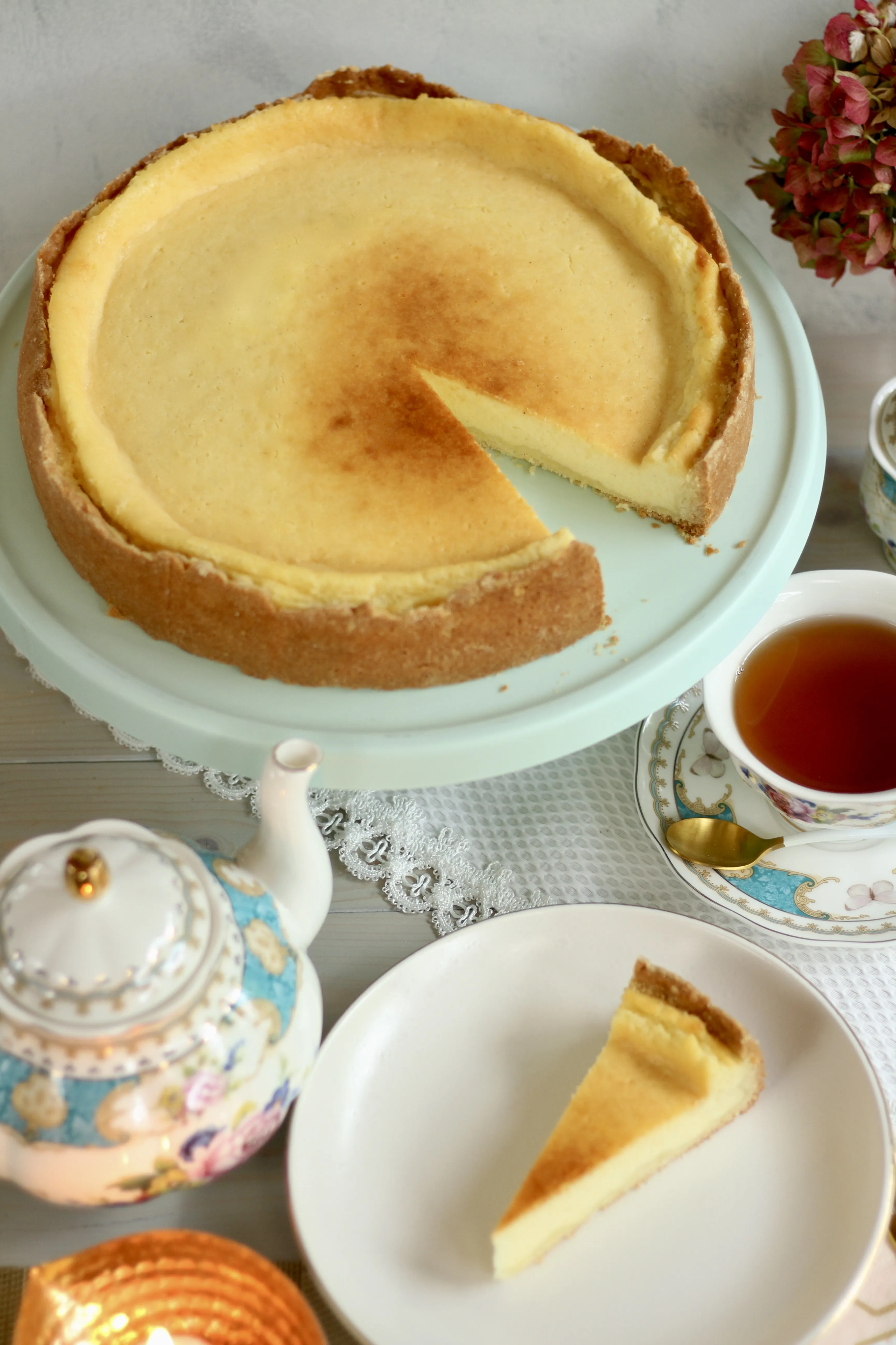 Ein ganzer, goldbrauner Käsekuchen auf einem rustikalen Holztisch