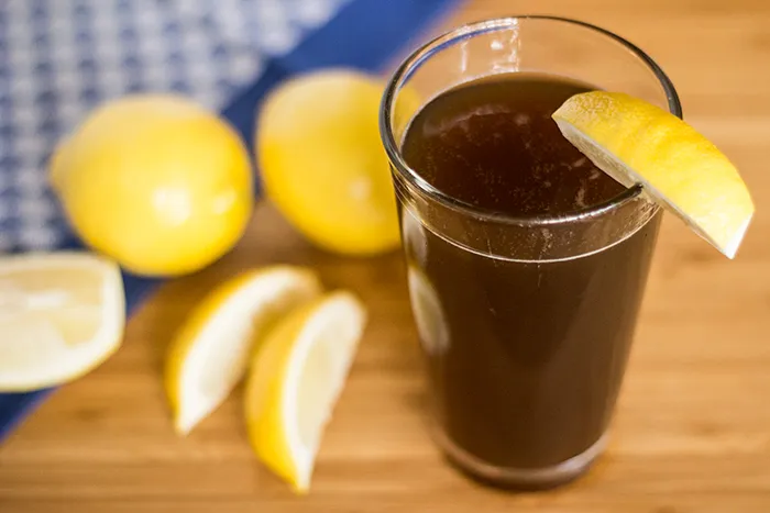 Ein Glas hausgemachte Cola Orange mit Eiswürfeln und Zitronenspalte, typisch deutsches Erfrischungsgetränk.