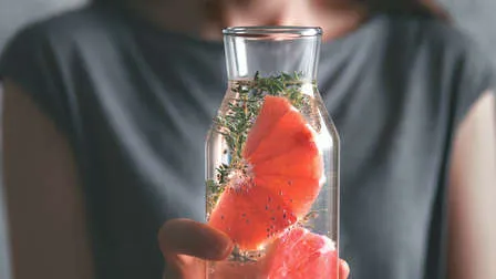 Ein Glas mit Chia-Wasser und Zitronenscheiben auf einem Holztisch, daneben eine Schale Chiasamen