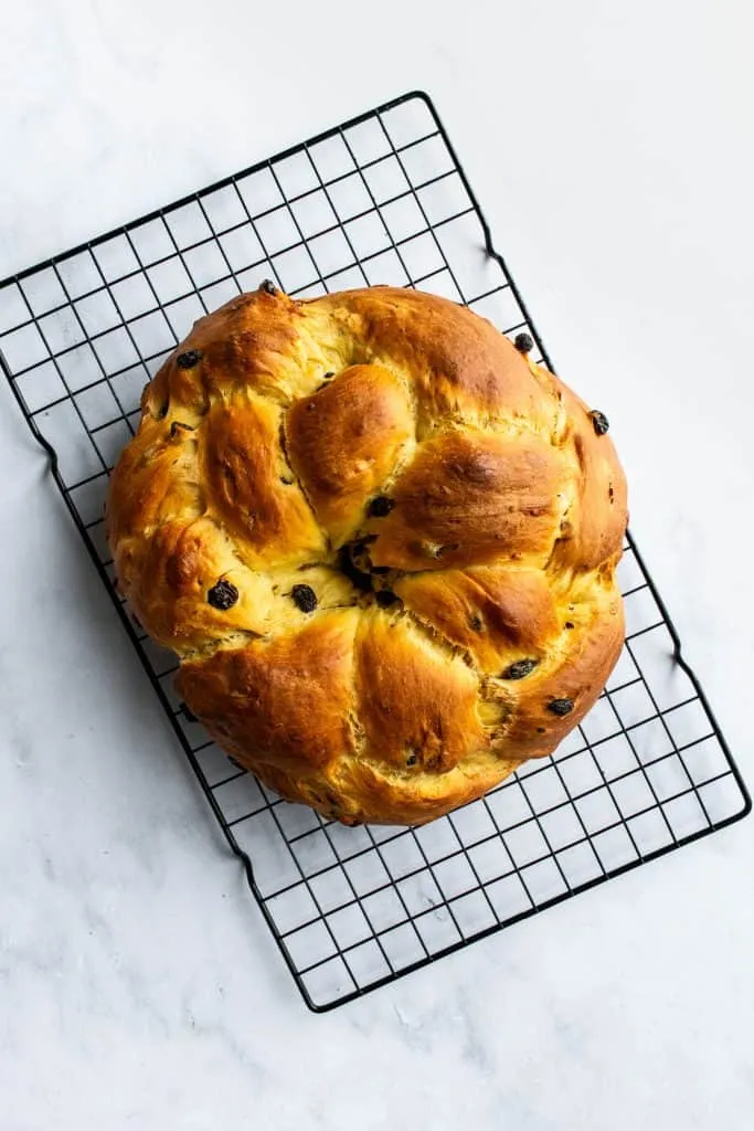 Ein goldbraun gebackener Osterkranz auf einem Metallrost, frisch aus dem Ofen, bereit zum Abkühlen und Bestreichen mit Aprikosenmarmelade.