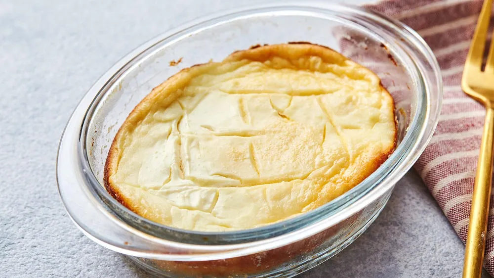 Ein goldbrauner, cremiger Quarkauflauf in einer rustikalen Auflaufform, perfekt für ein süßes Gericht.