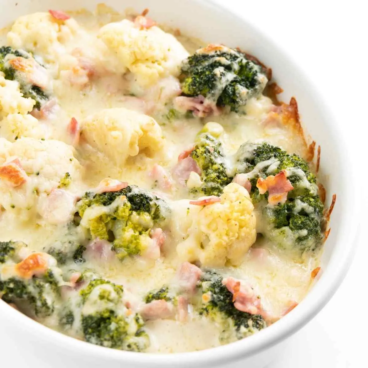 Ein goldbrauner Low Carb Blumenkohl-Brokkoli-Auflauf mit Käse überbacken und herzhaftem Schinken, ideal für die schnelle Familienküche