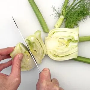 Ein halber Fenchel liegt auf einem Schneidebrett, bereit zum Zerkleinern und Hinzufügen zu Fischgerichten.