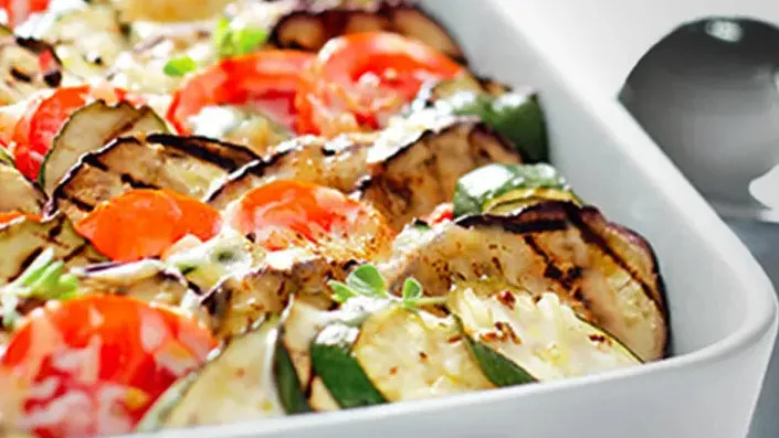 Ein herzhaftes Gemüsegratin mit frischer Zucchini, Aubergine und Tomaten in einer Auflaufform, verfeinert mit Quark.