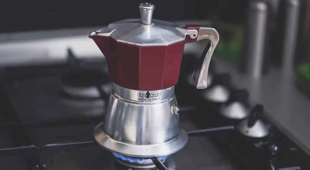 Ein italienischer Kaffeekocher brodelt auf einer Herdplatte und brüht frischen Mokka