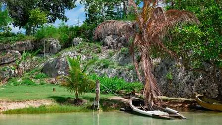 Ein kleines Boot gleitet auf einem ruhigen Fluss in der Nähe von Ocho Rios, Jamaika, umgeben von dichter tropischer Vegetation.
