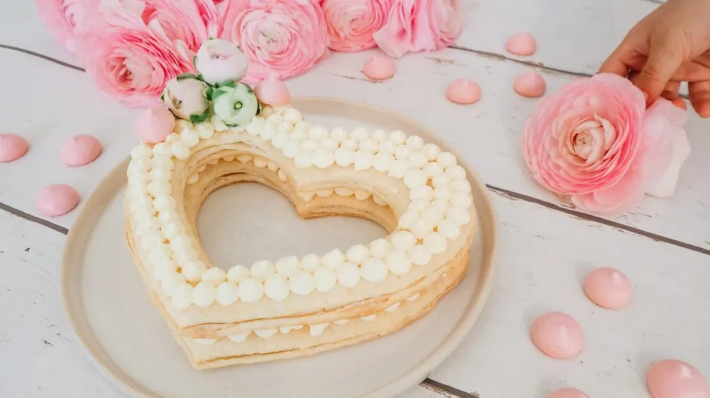 Ein liebevoll gebackener Herzkuchen mit Frischkäsefrosting und Beeren auf einer Tortenplatte