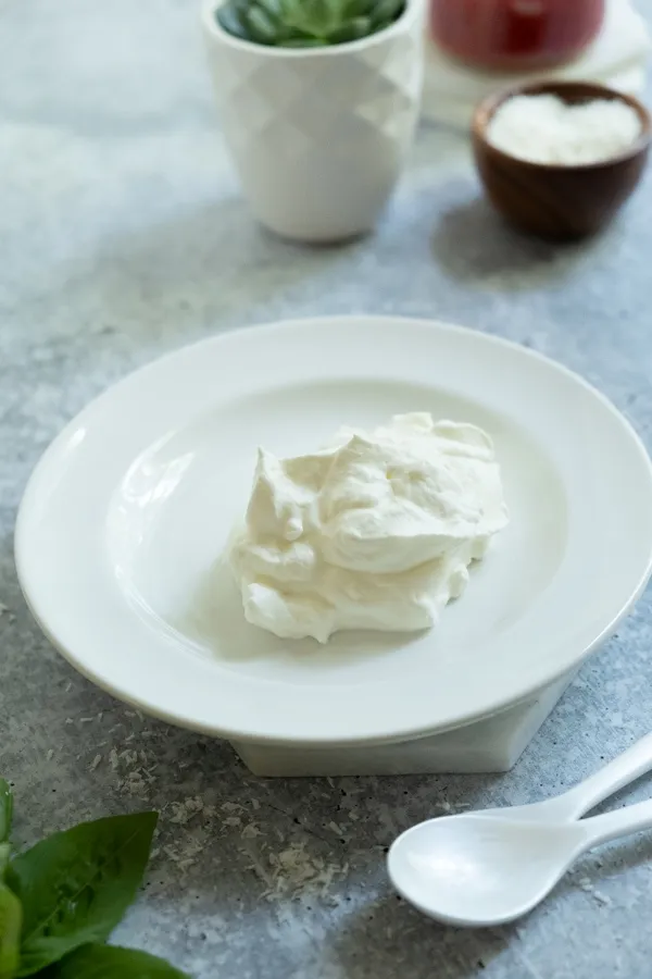 Ein Löffel Schlagsahne wird auf einen gekühlten Teller gegeben