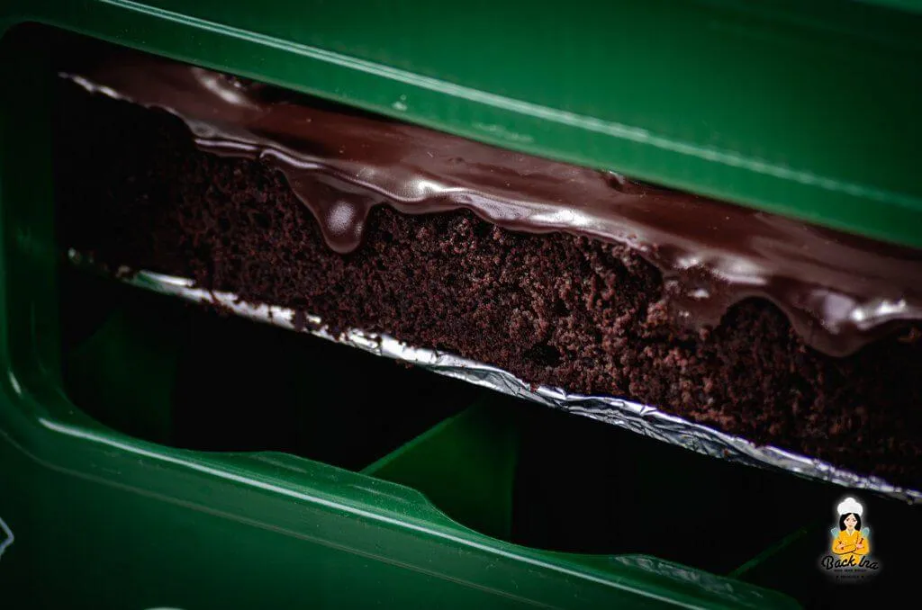 Ein Mann arrangiert die &quot;Flaschenhälse&quot; aus Schokoküssen und Kronkorken auf einer Torte, die in einen Bierkasten passt.