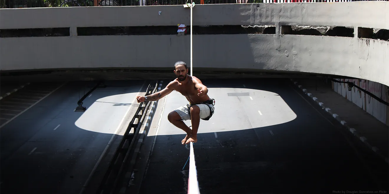 Ein Mann spannt eine Slackline über einer Straße