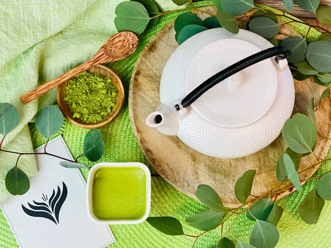 Ein Matcha-Tee in einer Tasse mit einem Teebesen daneben, bereit zur Zubereitung