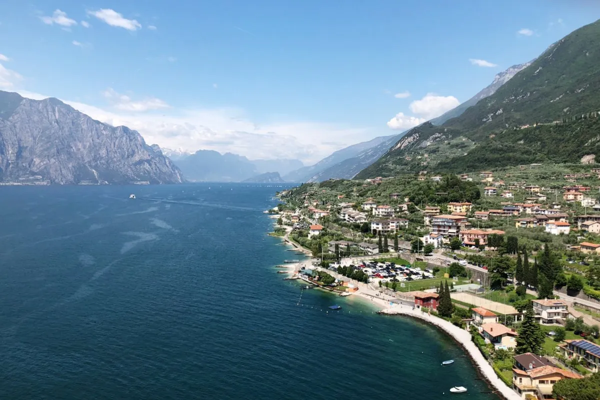 Ein Panoramablick auf den Gardasee, umgeben von grünen Bergen. Das türkisfarbene Wasser und die malerischen Dörfer am Ufer machen den Gardasee zu einem beliebten Urlaubsziel.