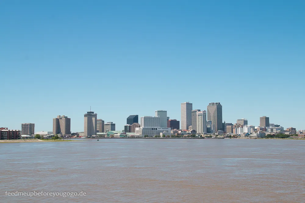 Ein Panoramablick auf die Skyline von New Orleans vom Mississippi aus gesehen, mit industriellen und städtischen Elementen.