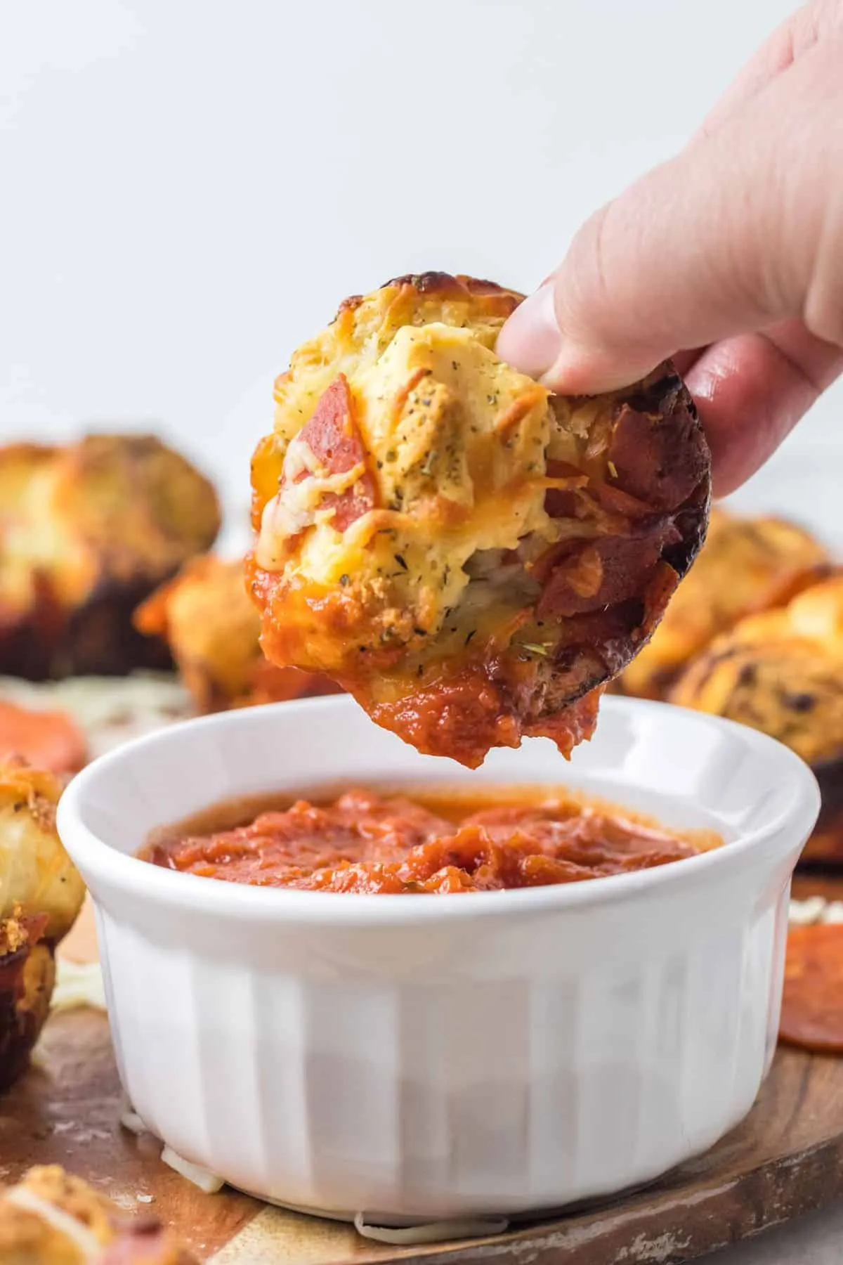 Ein Pizza Muffin wird in eine Schale mit Marinara-Sauce getaucht.