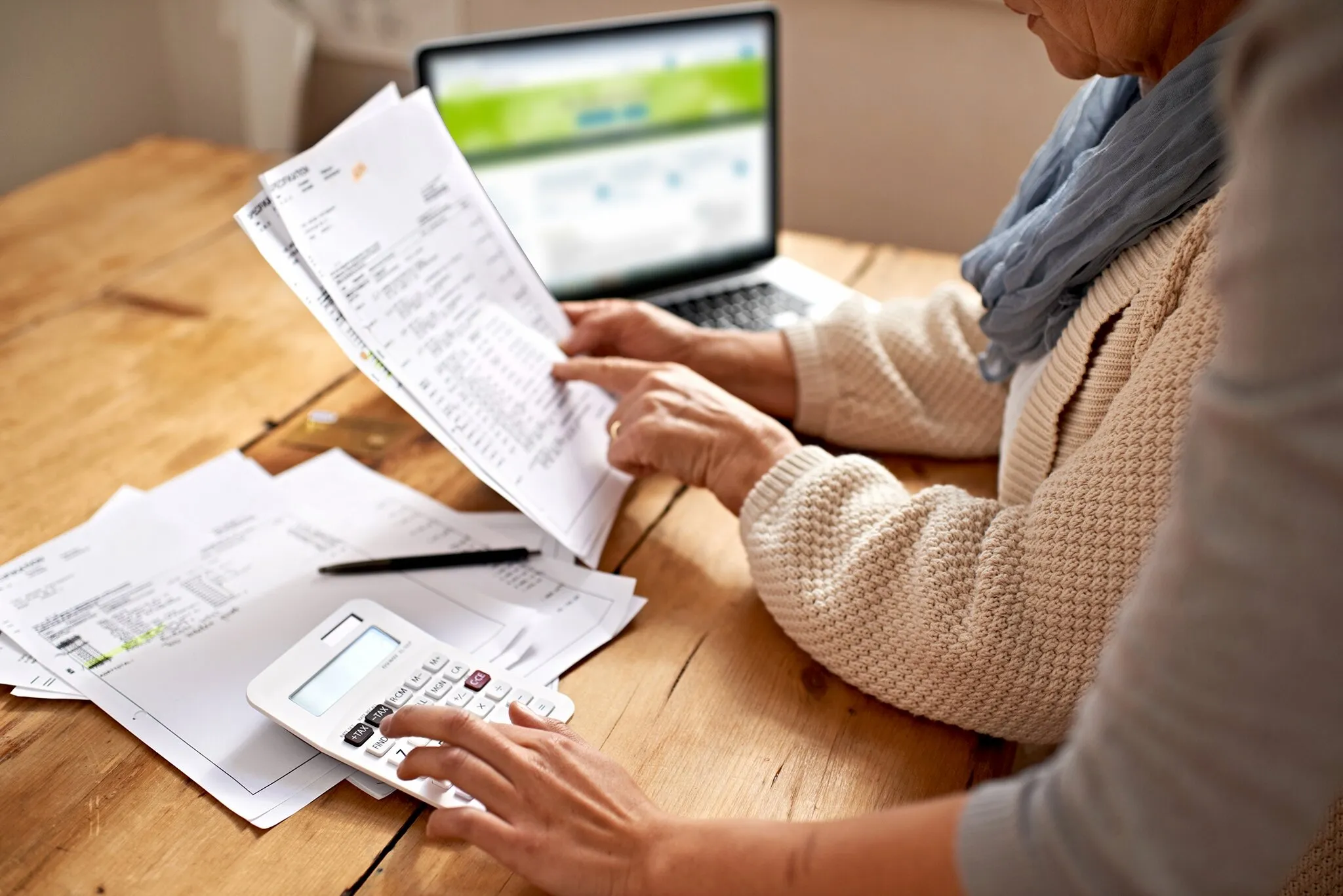 Ein Rentner sitzt am Schreibtisch und bearbeitet seine Steuererklärung, um seine Steuerlast zu ermitteln.