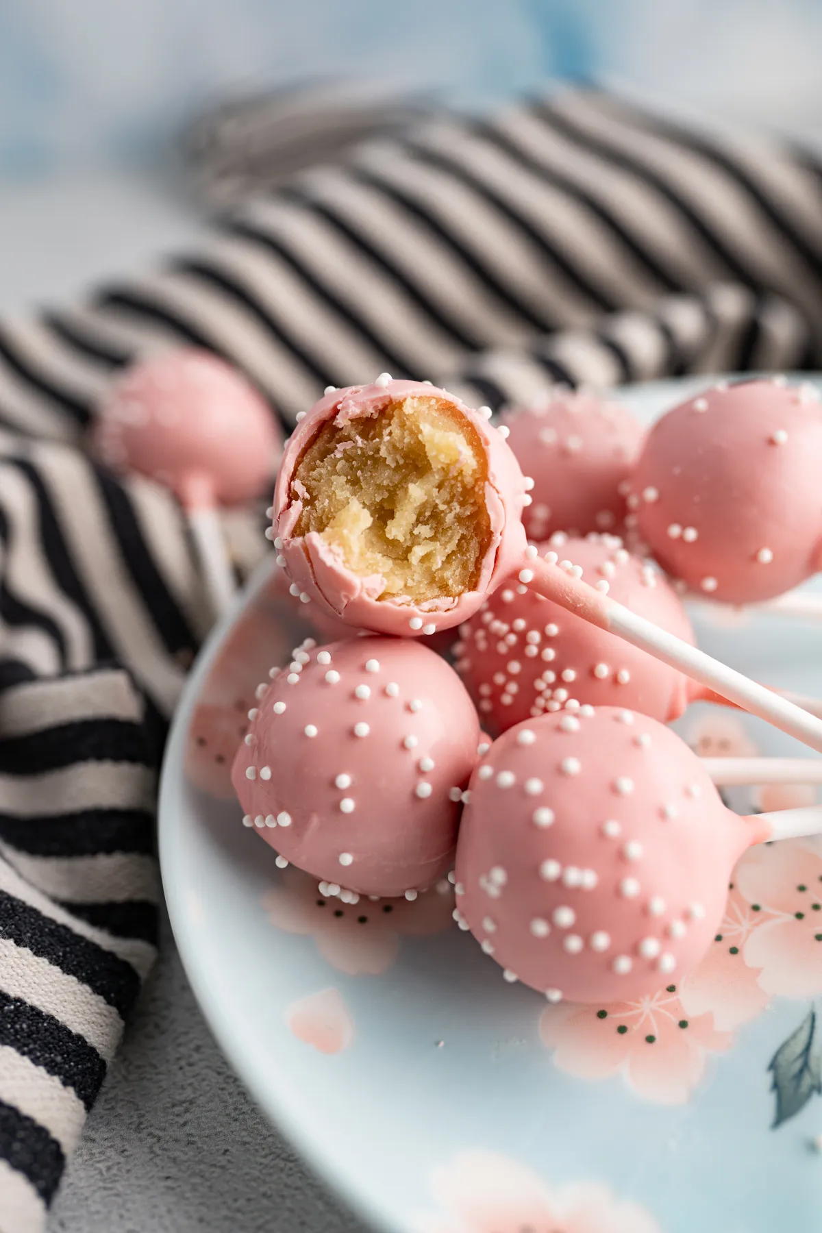 Ein rosa Starbucks Birthday Cake Pop Duplikat auf einem Teller, von dem ein Stück abgebissen wurde.