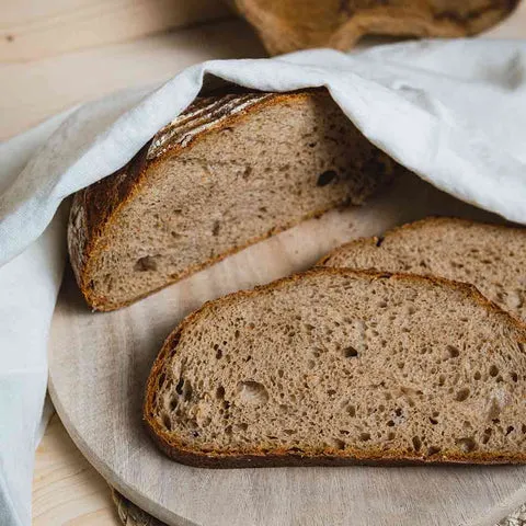 Ein rustikales Bauernbrot mit kräftiger Kruste auf einem Holzbrett, bereit zum Anschneiden.