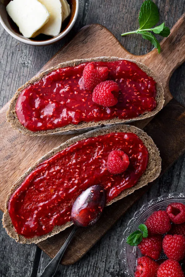 Ein rustikales Brot mit einer dicken Schicht selbstgemachter Himbeermarmelade, ideal für ein deutsches Frühstück.