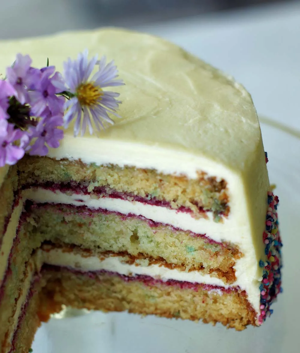 Ein saftiger Anschnitt des amerikanischen Funfetti Geburtstagskuchens mit bunter Creme und Streuseln