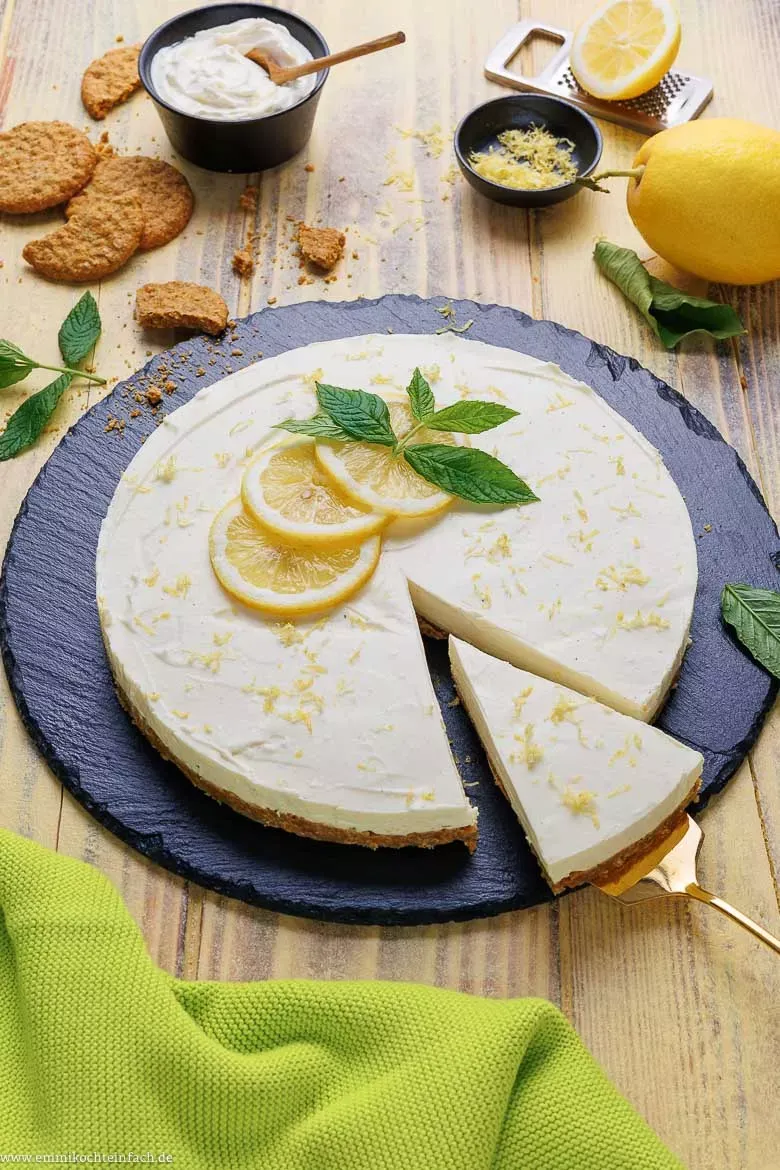 Ein saftiger Philadelphia Kuchen mit Zitronennote auf einem rustikalen Holztisch, dekoriert mit frischen Minzblättern und Zitronenscheiben.