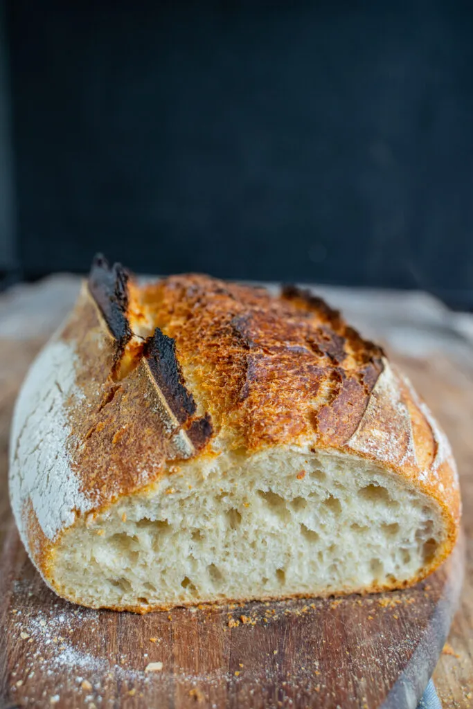 Ein Sauerteigbrot wird aus einem Gärkorb auf ein Backblech gestürzt.