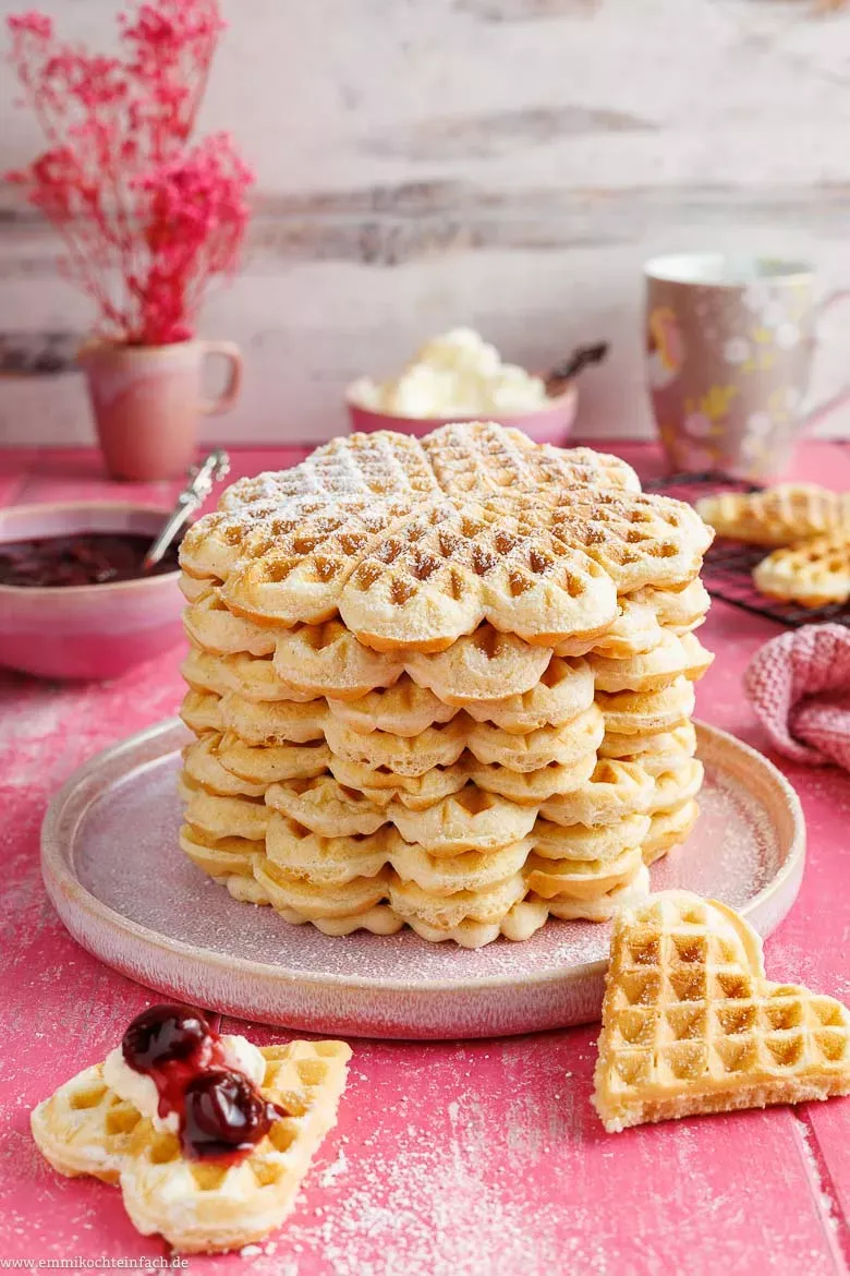 Ein Stapel fluffiger Waffeln mit Puderzucker und frischen Kirschen, bereit zum Genießen