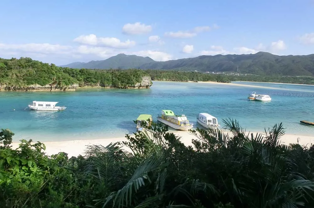 Ein Strand auf Okinawa, Japan, mit weißem Sand und türkisfarbenem Wasser unter einem blauen Himmel.