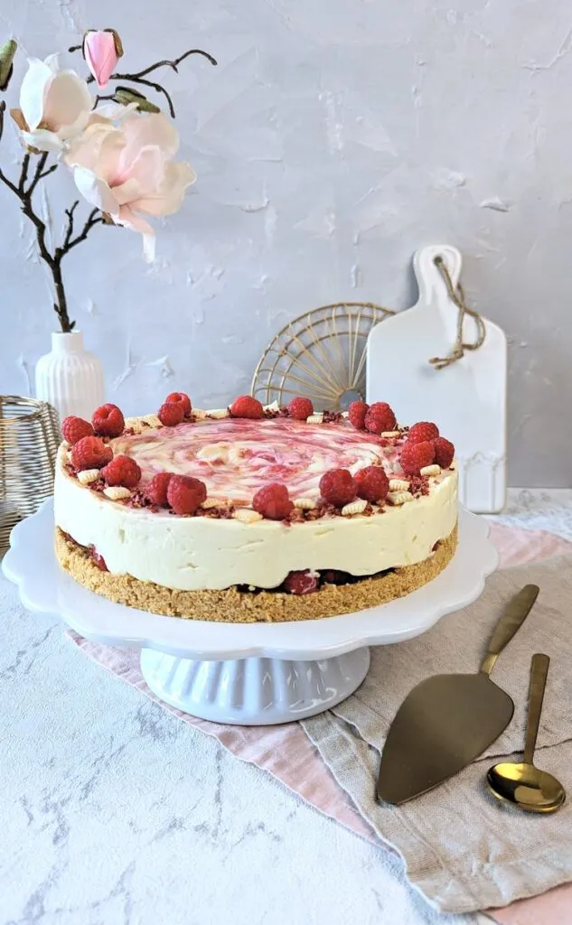 Ein Stück cremiger Geburtstagskuchen mit weißer Schokolade und frischen Himbeeren, bereit zum Genießen.