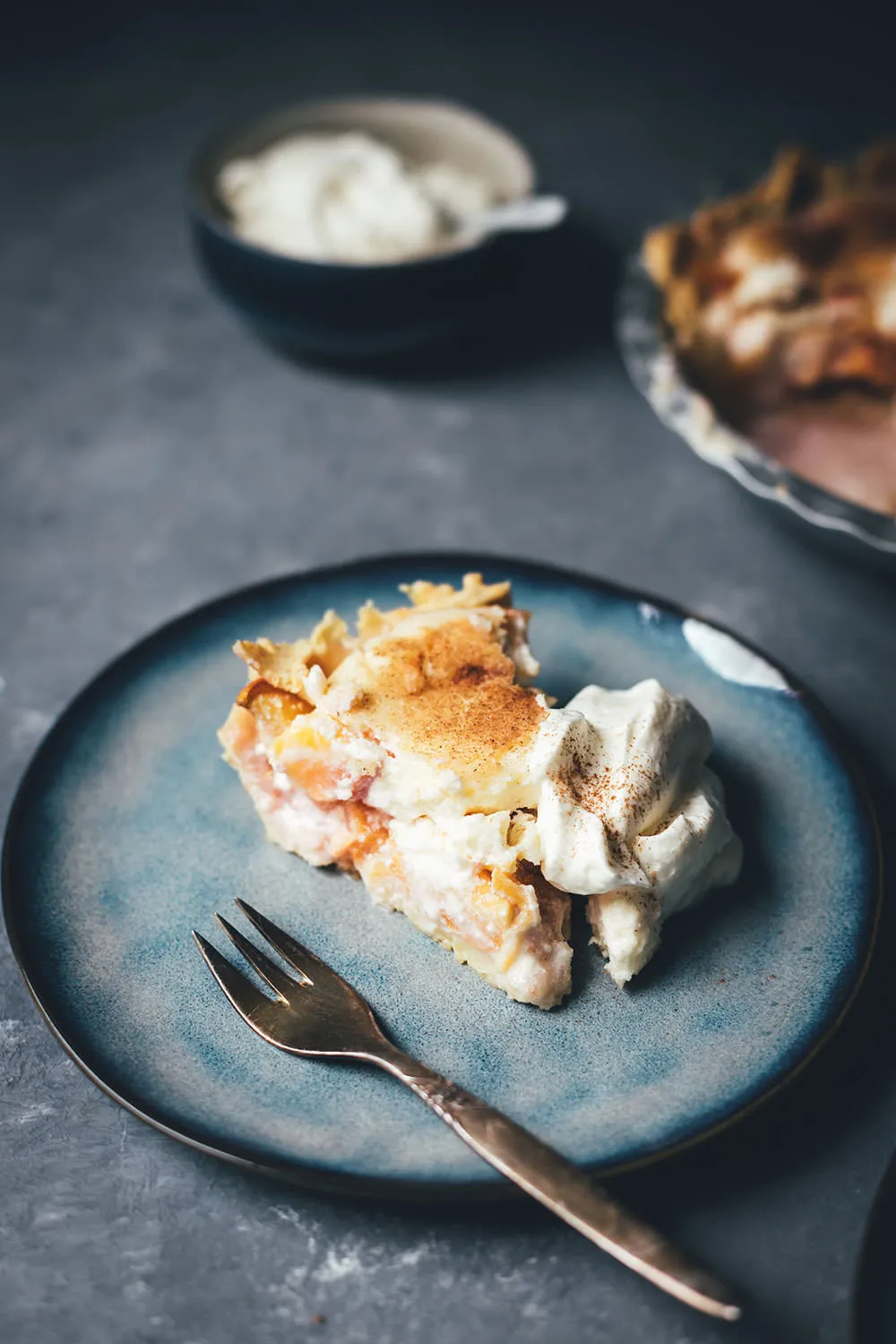 Ein Stück des sommerlichen Pfirsichkuchens (Peaches and Cream Pie) auf einem Teller, serviert mit Schlagsahne.