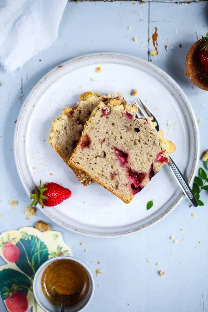 Ein Stück Erdbeer-Bananenbrot mit Streuseln, aufgeschnitten, das die weiche, fruchtige Textur und die süßen Erdbeeren zeigt. Perfekt für den Nachmittagskaffee.