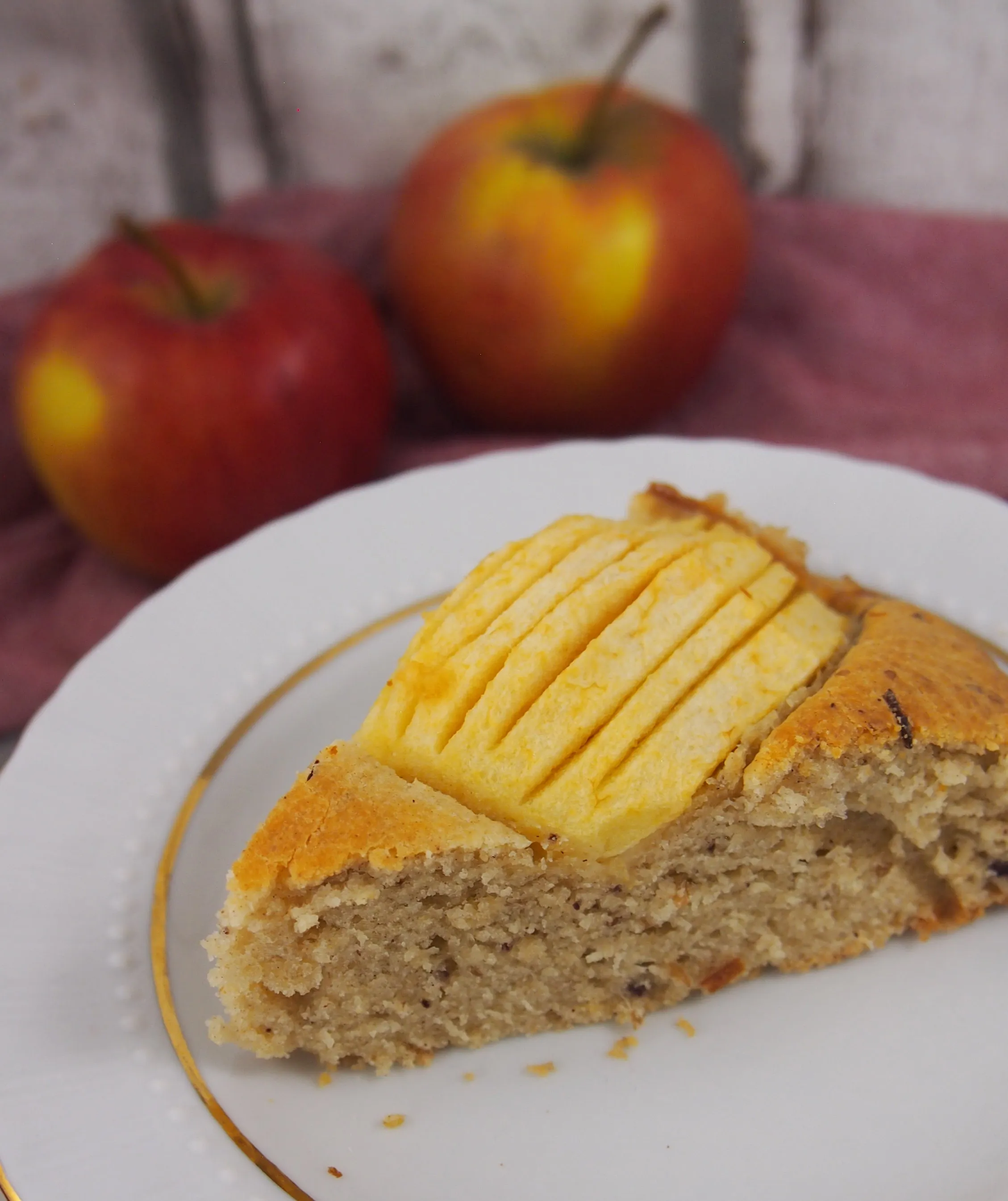 Ein Stück flaumiger Apfelkuchen ohne Zucker auf einem Teller, der die weiche und feuchte Konsistenz des Teigs und die fruchtige Füllung zeigt.