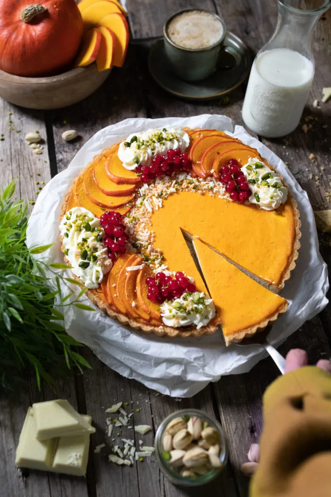 Ein Stück herbstlicher Pistazien-Kürbis-Cheesecake mit Sahnetupfen, ein Genuss zur Kaffeezeit.