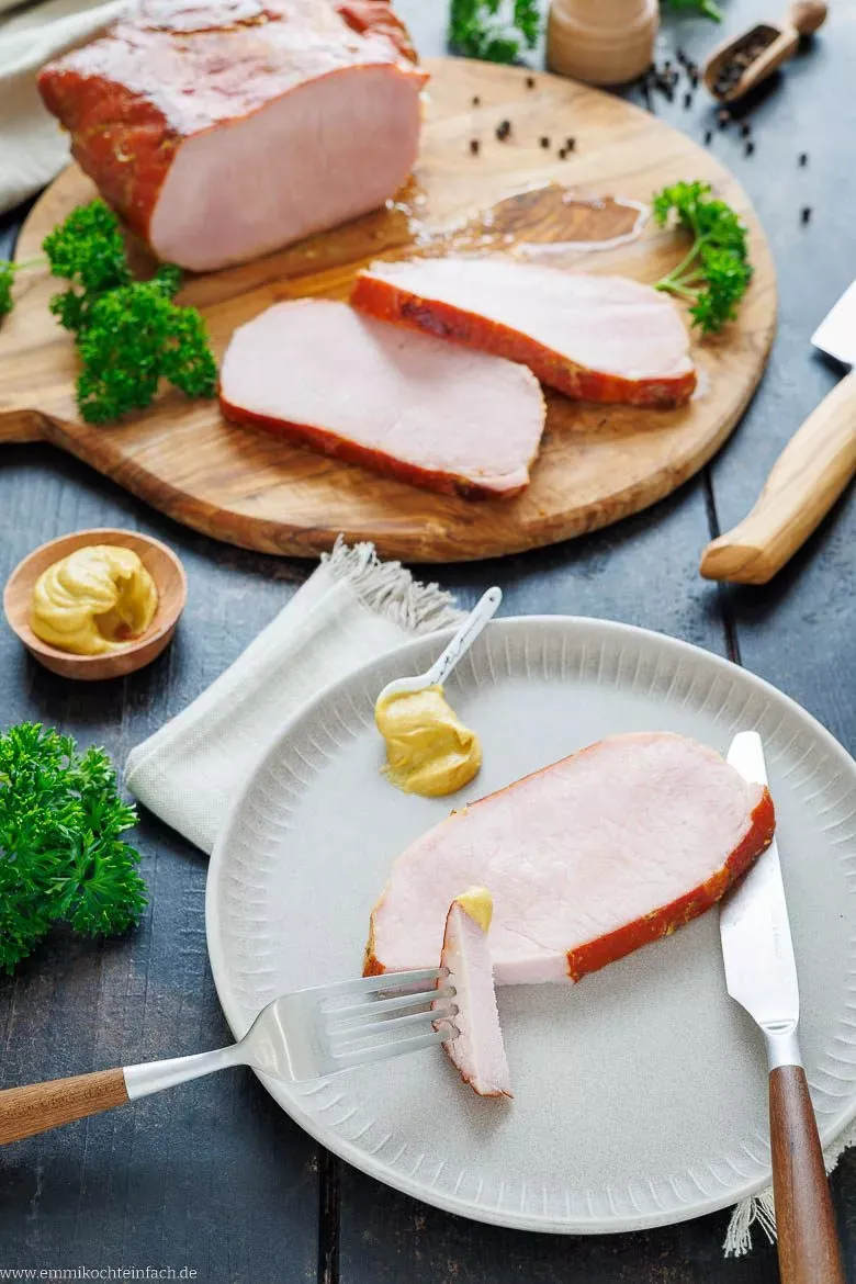 Ein Stück Kassler mit einem Klecks scharfem Senf auf einem Teller, perfekt als Beilage.