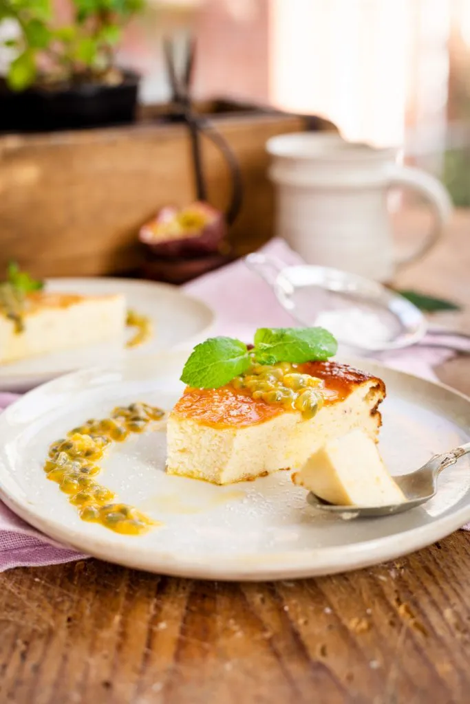 Ein Stück Low Carb Käsekuchen ohne Boden auf einem weißen Teller, dekoriert mit Minze