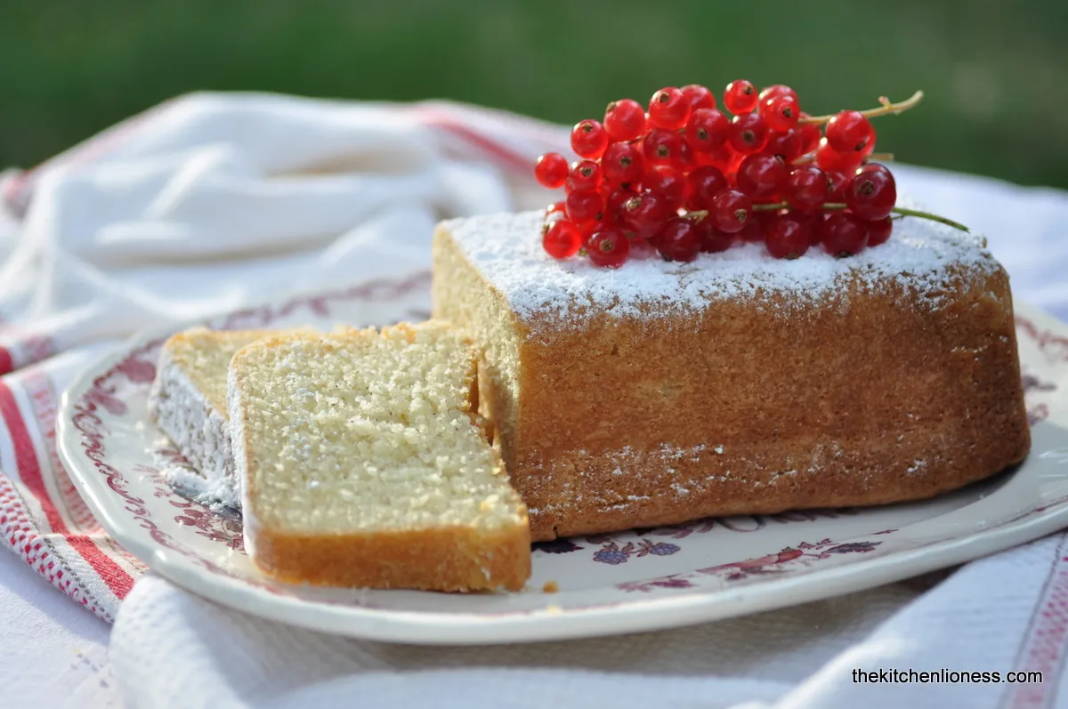 Ein Stück Salzbutterkuchen mit Puderzucker und frischen roten Johannisbeeren