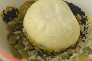 Ein Teigling wird in eine Schale mit gemischten Körnern getaucht