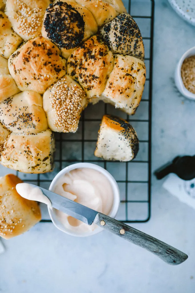 Ein Teller mit aufgeschnittenem Brötchenkranz, die einzelnen Brötchen sind mit unterschiedlichen Toppings versehen und laden zum Zugreifen ein.