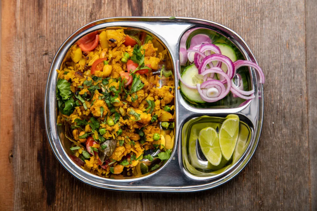 Ein Teller mit Poha, einem indischen Frühstücksgericht aus Reisflocken.