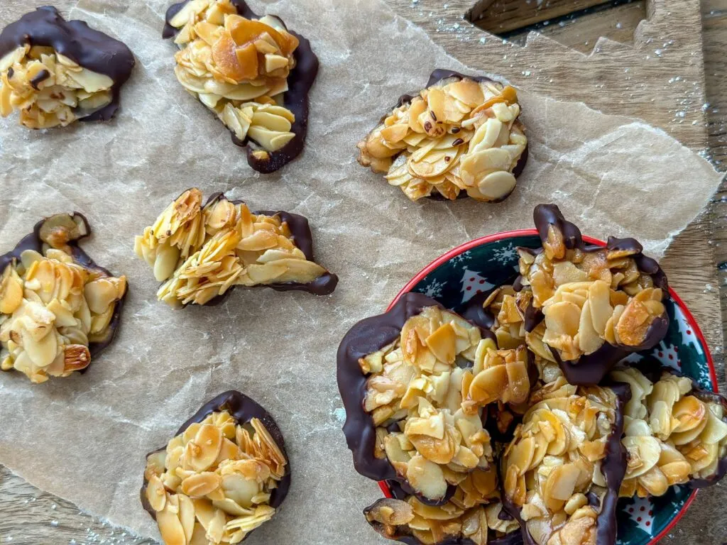 Ein Teller voller knuspriger Florentiner Plätzchen, teils mit dunkler Schokolade überzogen, festlich arrangiert für die Weihnachtszeit.