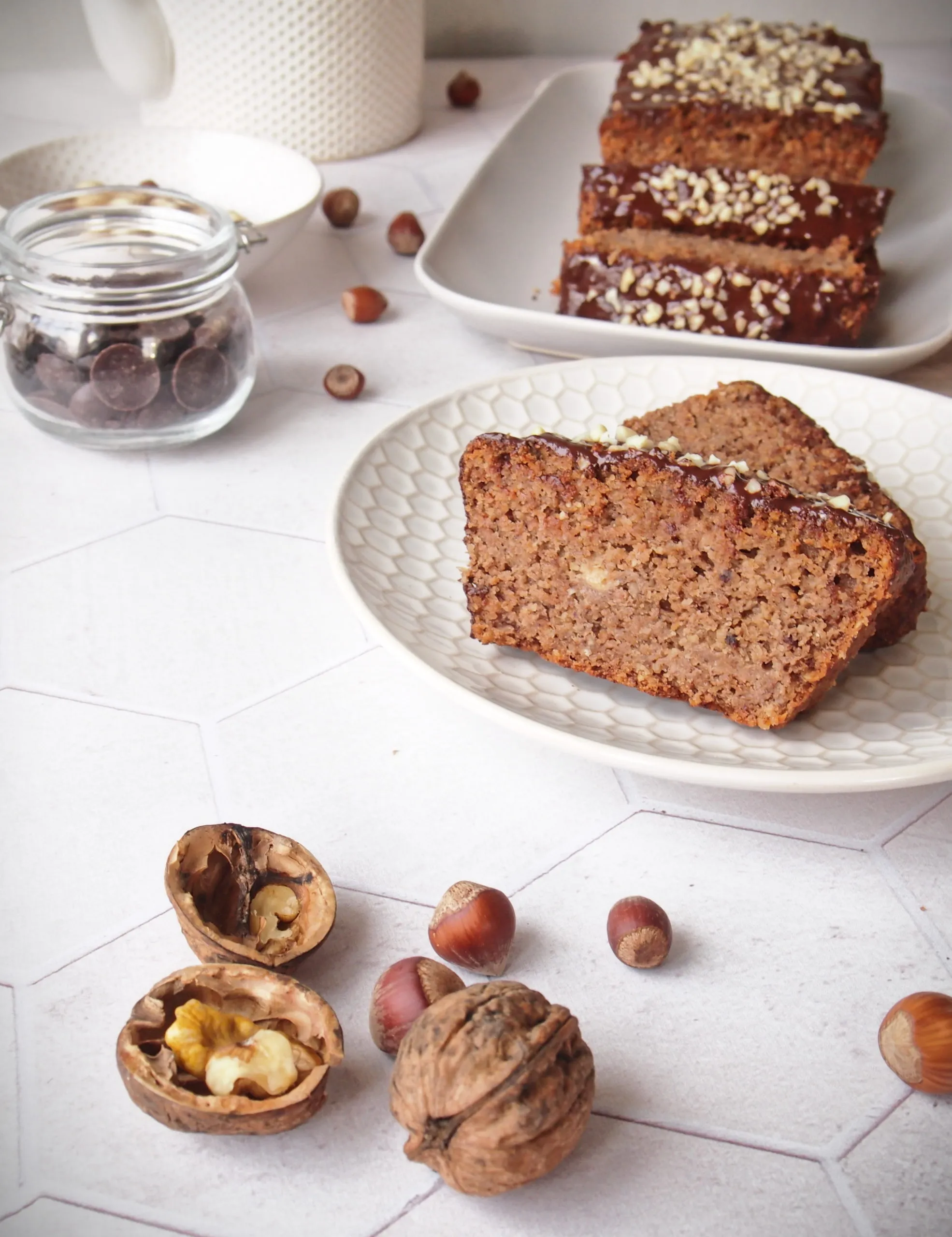 Ein von oben aufgenommener veganer Nusskuchen, verziert mit Schokoglasur und gehackten Nüssen