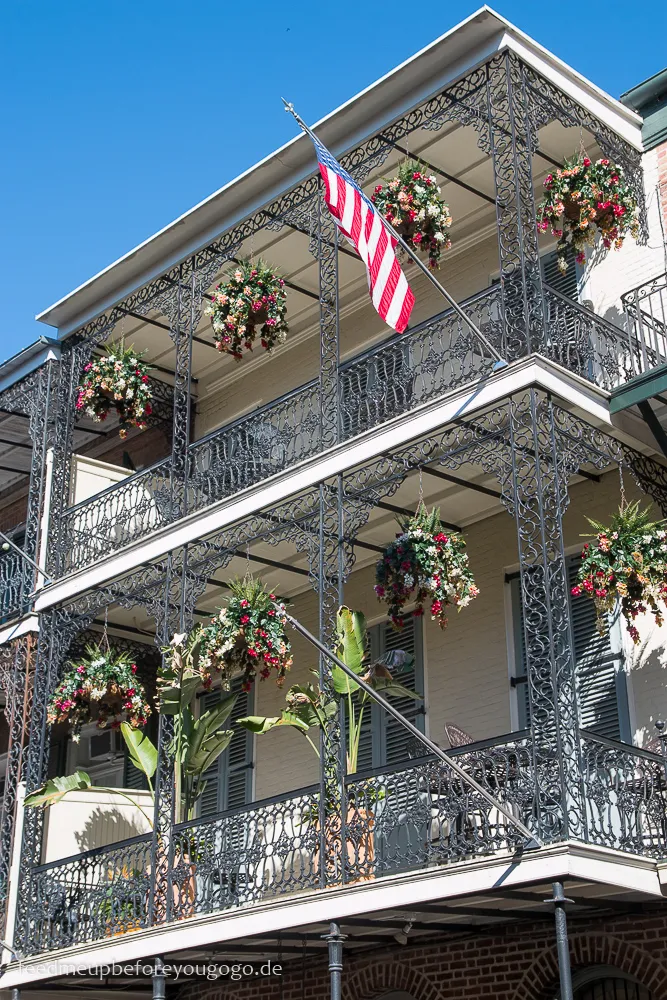 Ein weiterer Detailblick auf einen Balkon im French Quarter, der die kunstvolle Eisenarbeit und das grüne Ambiente von New Orleans zeigt.