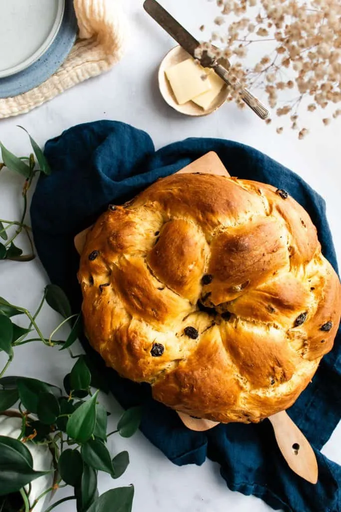 Ein wunderschön geflochtener und fertig gebackener Osterkranz auf einem rustikalen Holzbrett, ein Blickfang für jede Ostertafel.