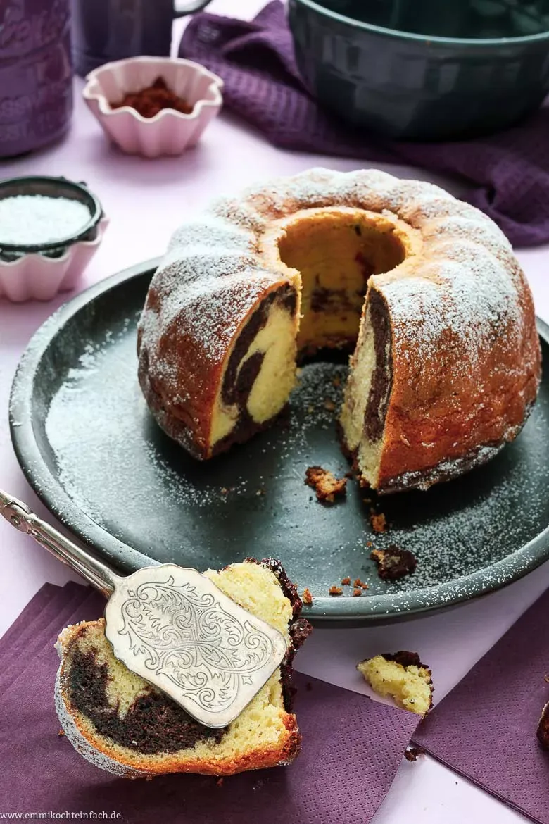Ein wunderschön verzierter Mini-Marmorkuchen in einer kleinen Gugelhupf-Form, bestäubt mit Puderzucker.