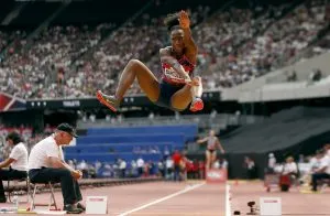 Eine Athletin im Flug während eines Weitsprungs über einer Sandgrube, kurz vor der Landung
